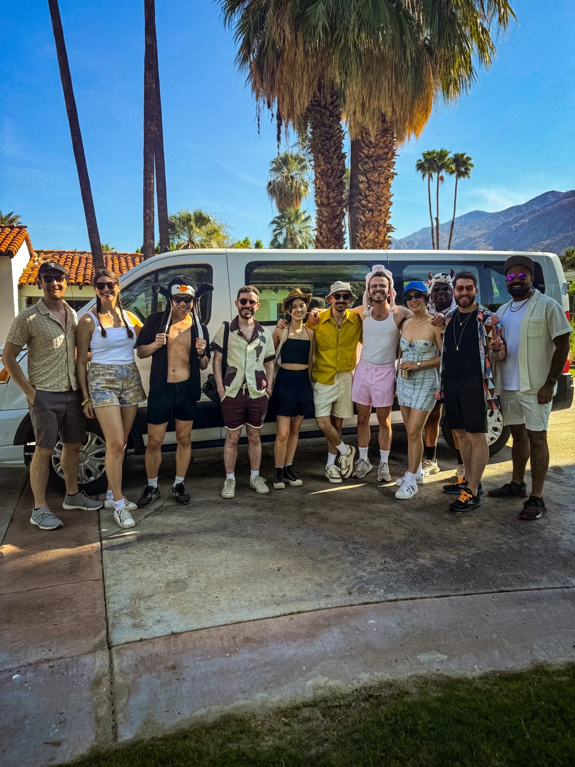 Large group of Coachella guests in front of white van with palm trees