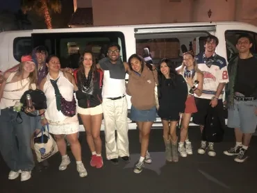 Group of Coachella guests posing in front of white van at night